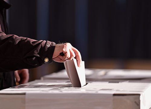 Close up of a mans hand putting a piece of paper in to a drop box.