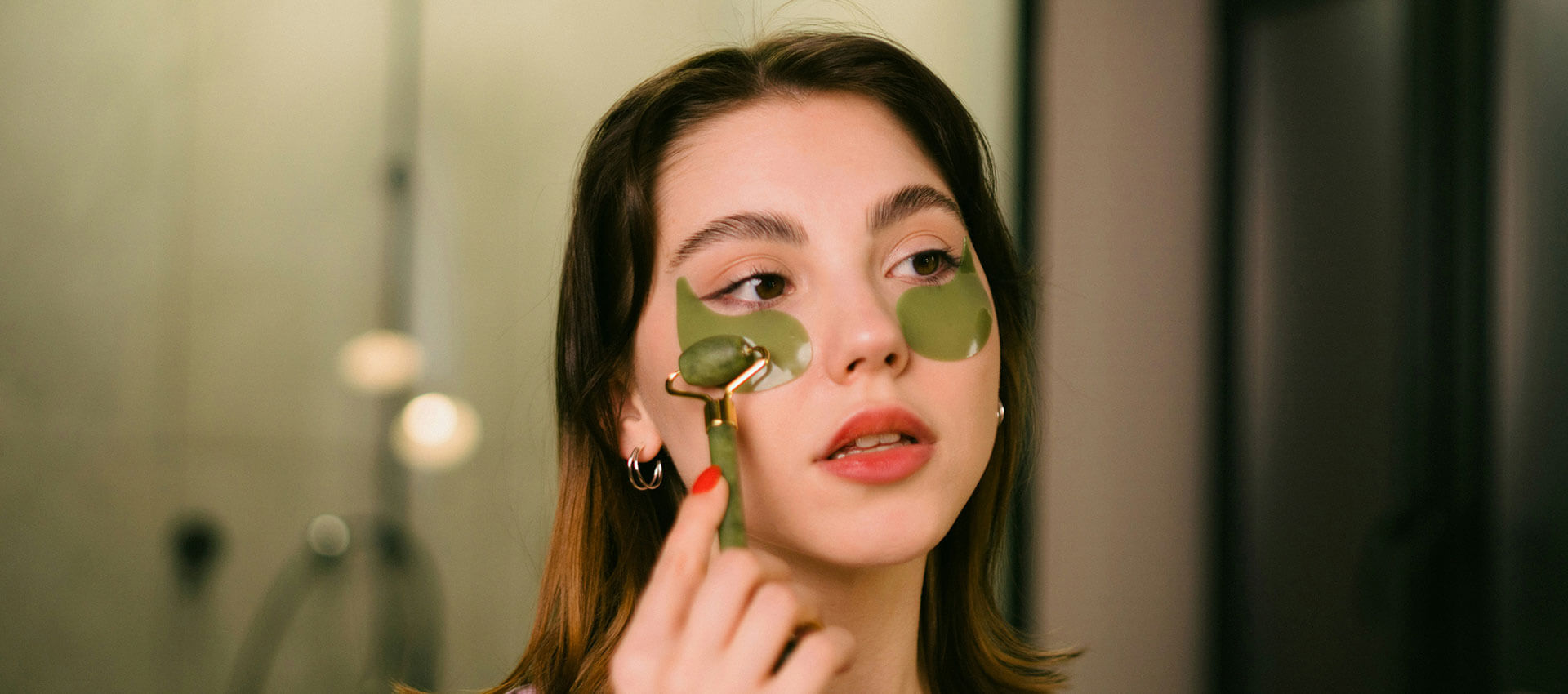 A person stands outside a rain-streaked window, touching the glass. They gaze thoughtfully inside, with a dimly lit room visible in the background.