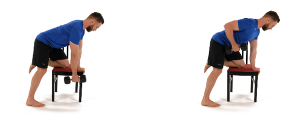 Man wearing a blue shirt and black shorts demonstrates a dumbbell row exercise using a chair for support. The setting is a plain white background.