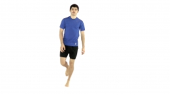 A person wearing a blue shirt and black shorts balances on one leg, set against a plain white background.