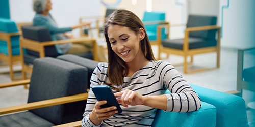 A woman in a striped shirt smiles while holding a phone
