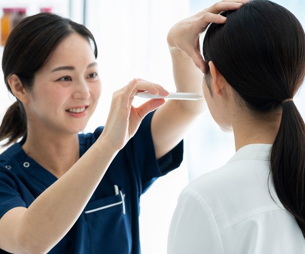 A healthcare professional uses a forehead thermometer on a patient in a clinical setting, ensuring precise temperature measurement in a well-lit examination room.